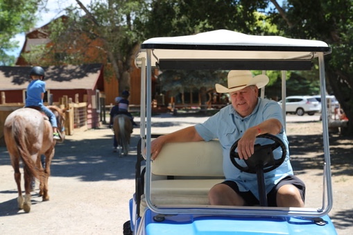 Ed sitting in a golf cart wearing a cowboy hat