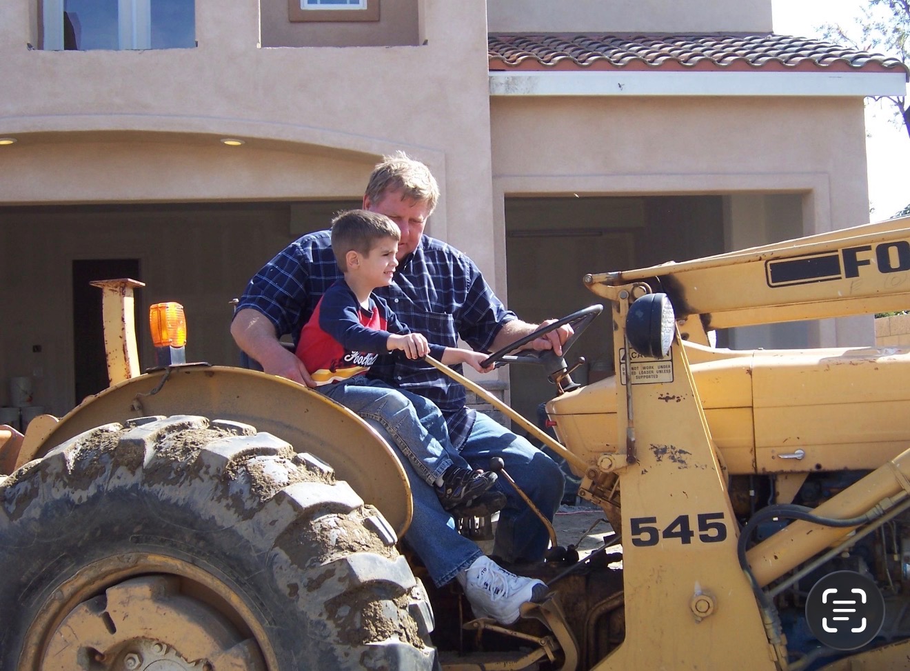 Ed and a young boy driving a tractor together